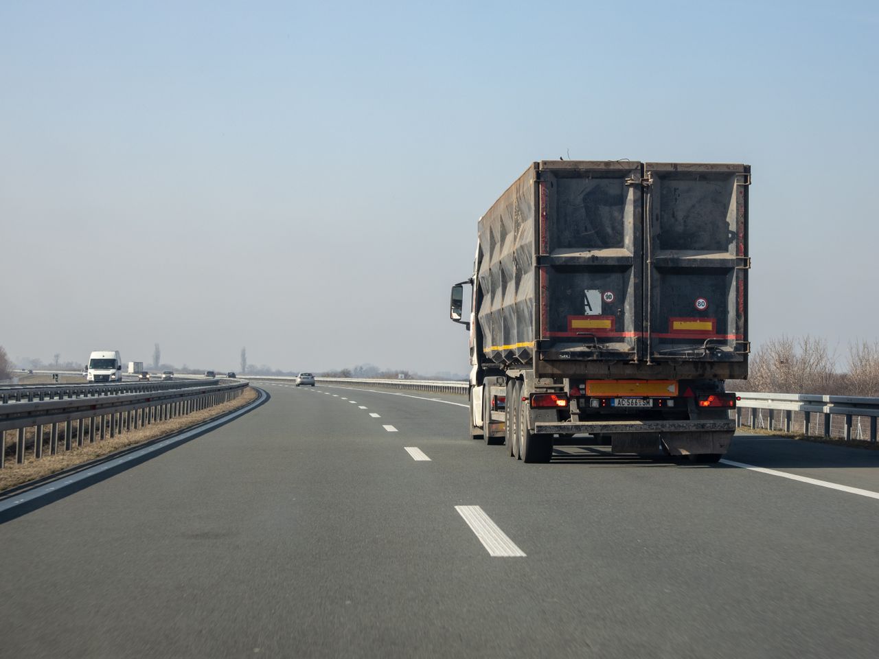 Services A cargo truck travels down an empty highway on a clear day, showcasing transportation and logistics.