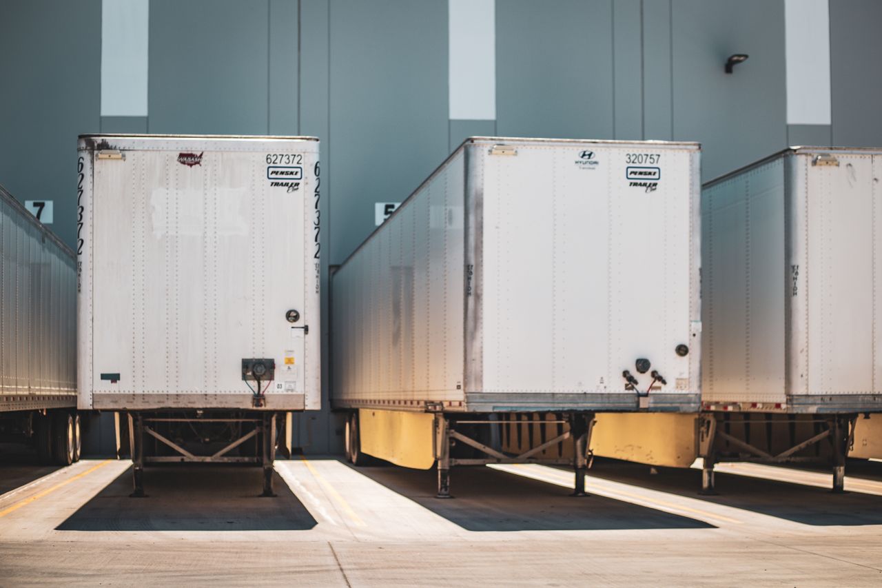 Services A row of freight trailers parked at a commercial loading dock, emphasizing transportation and logistics.